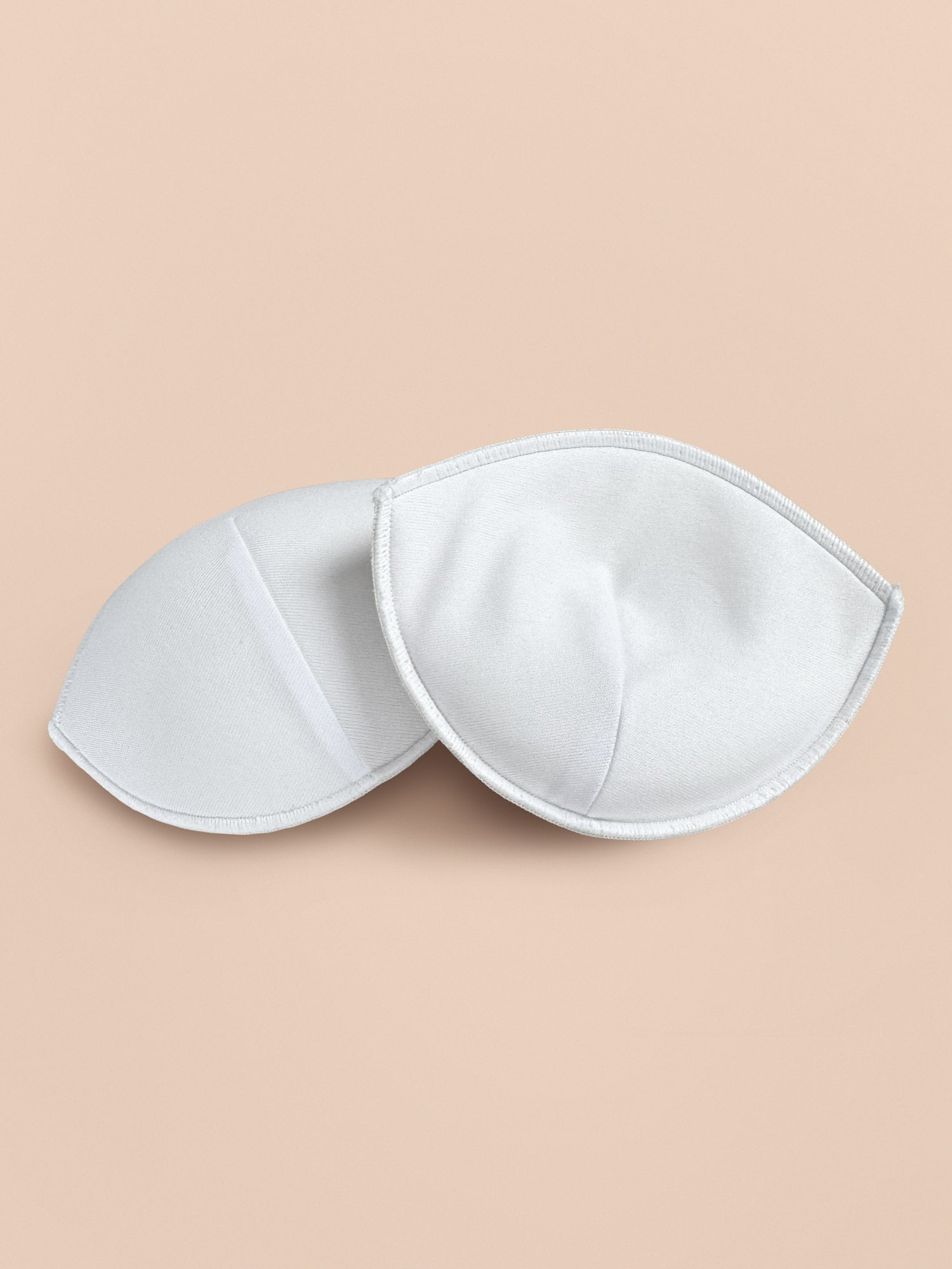 Interior view of thick foam Bra inserts with white cloth-covering for enhancing cleavage and adding volume.